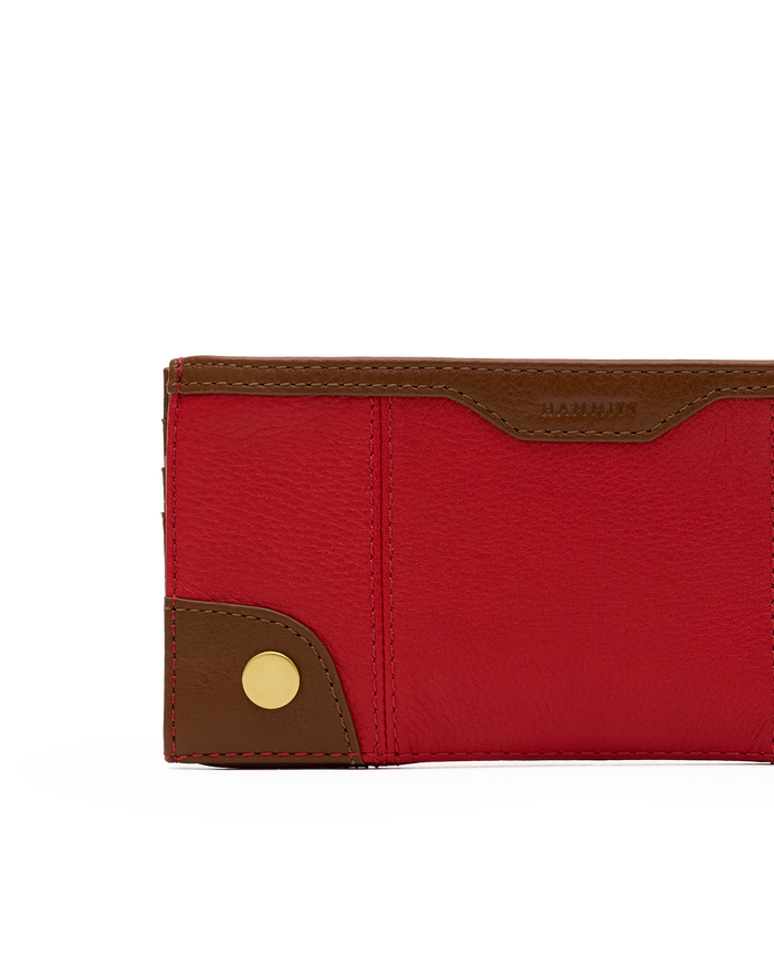 A close-up of a red pebbled leather wallet with brown leather trim and a gold snap button, on a white background.