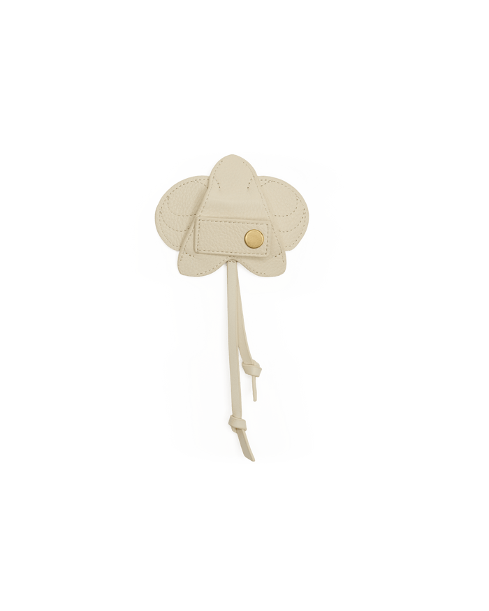 Beige hat with a button on a white stand against a black background