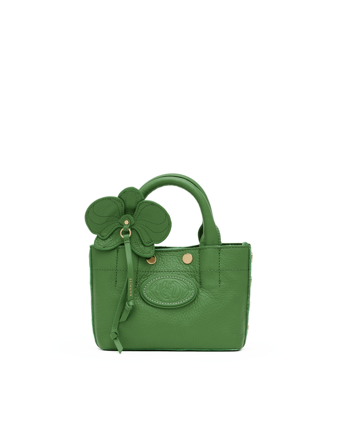 Green handbag with floral design on a white platform against a black background