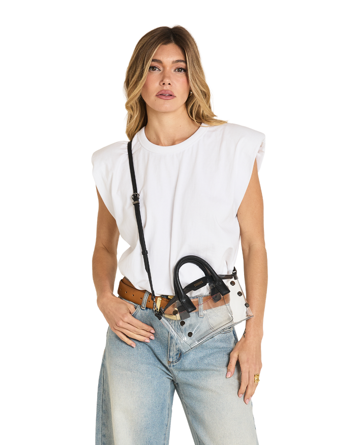 A woman modeling a white sleeveless top, light-wash blue jeans, a brown belt, and a clear crossbody bag with black hardware and strap.