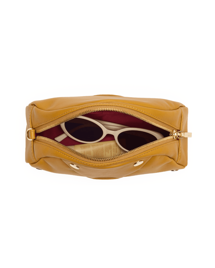 Yellow handbag with sunglasses inside on a white background