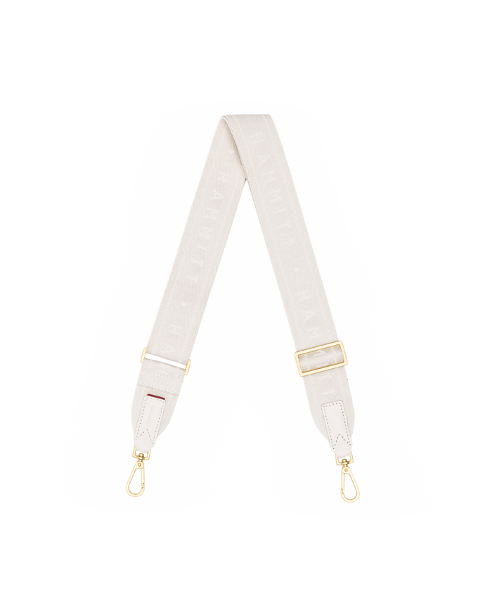 A light beige fabric shoulder strap with gold-tone hardware, featuring a repeating monogram pattern and adjustable metal buckles.